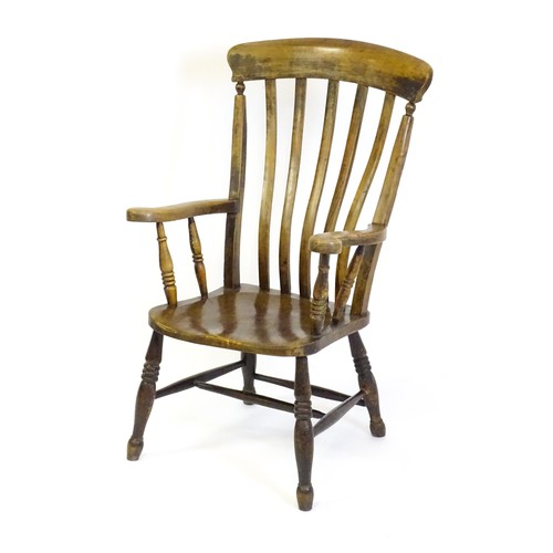 1516 - A late 19thC / early 20thC lathe back Windsor armchair, with swept arms, a shaped seat and raised on... 