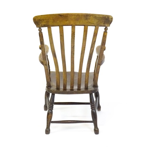 1516 - A late 19thC / early 20thC lathe back Windsor armchair, with swept arms, a shaped seat and raised on... 