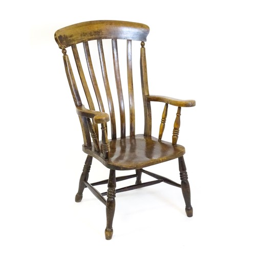 1516 - A late 19thC / early 20thC lathe back Windsor armchair, with swept arms, a shaped seat and raised on... 