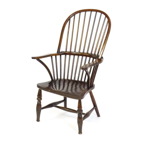 1556 - A 19thC double bow back Windsor chair, having a stick back, swept arms, a shaped seat and raised on ... 