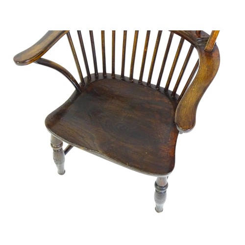 1556 - A 19thC double bow back Windsor chair, having a stick back, swept arms, a shaped seat and raised on ... 