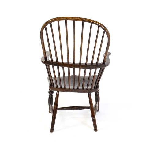 1556 - A 19thC double bow back Windsor chair, having a stick back, swept arms, a shaped seat and raised on ... 