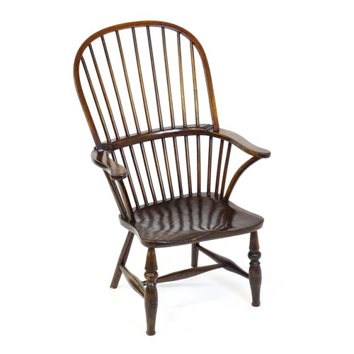 1556 - A 19thC double bow back Windsor chair, having a stick back, swept arms, a shaped seat and raised on ... 