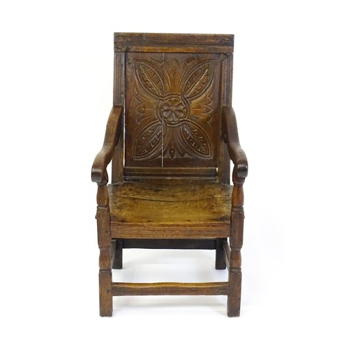 1558 - A 17thC oak Wainscot chair with a panelled, carved backrest above shaped arms and an incised frame, ... 