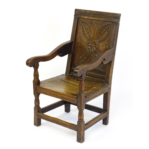 1558 - A 17thC oak Wainscot chair with a panelled, carved backrest above shaped arms and an incised frame, ... 