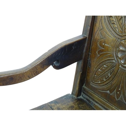 1558 - A 17thC oak Wainscot chair with a panelled, carved backrest above shaped arms and an incised frame, ... 