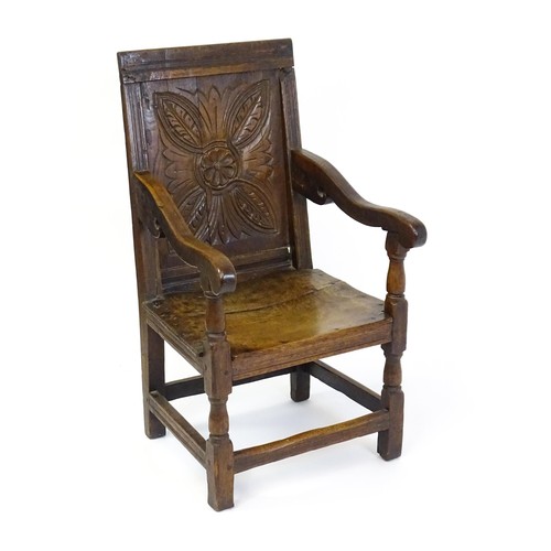 1558 - A 17thC oak Wainscot chair with a panelled, carved backrest above shaped arms and an incised frame, ... 