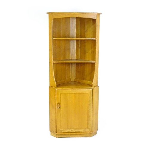 1628 - Vintage / Retro: An elm Ercol Windsor corner cabinet with a moulded cornice above three shelves and ... 