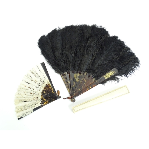 1119 - An early 20thC black feather fan with 20 faux tortoiseshell sticks. Together with another smaller ex... 