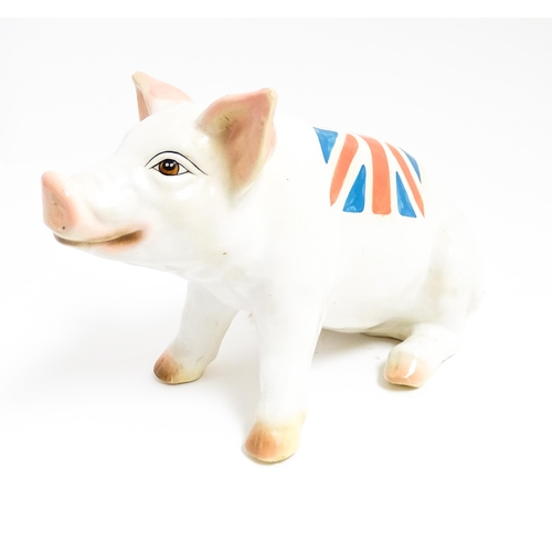 1131 - A 20thC butcher's advertising ceramic model of a seated pig with painted features and Union Jack fla... 