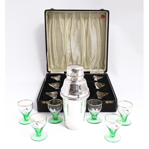 1145 - A cased Art Deco cocktail set comprising a silver plate cocktail shaker with six green footed glasse... 