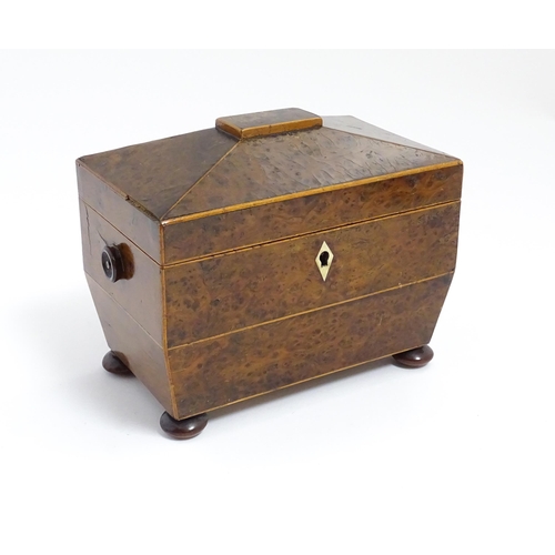 1248 - A late 19th / early 20thC burr walnut tea caddy of sarcophagus form with squat bun feet, opening to ... 