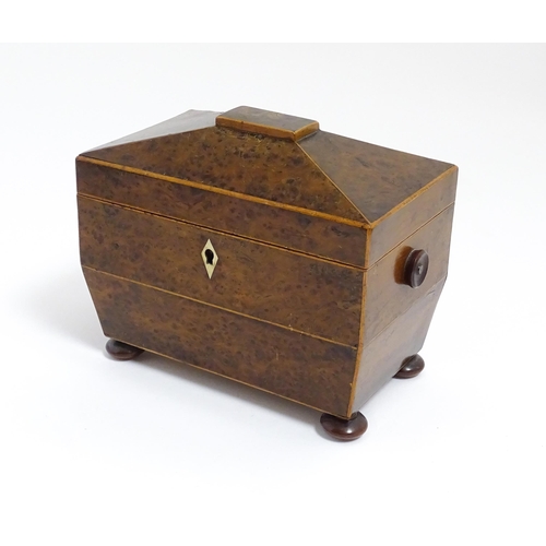 1248 - A late 19th / early 20thC burr walnut tea caddy of sarcophagus form with squat bun feet, opening to ... 