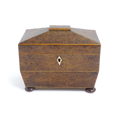 1248 - A late 19th / early 20thC burr walnut tea caddy of sarcophagus form with squat bun feet, opening to ... 