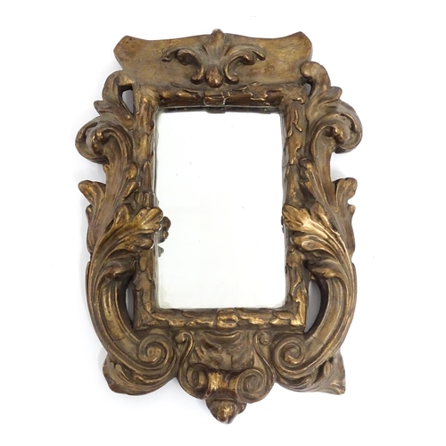 1258 - A late 19th / early 20thC carved giltwood and gesso framed mirror with acanthus leaf and scroll deco... 