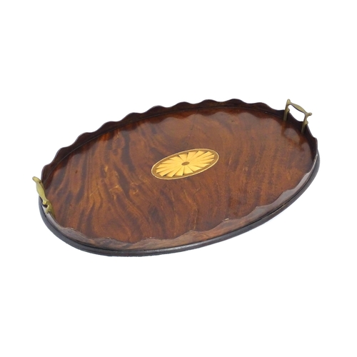 1262 - A Victorian mahogany tray of oval form with scalloped edge gallery, twin brass handles and inlaid sh... 