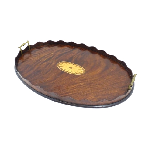 1262 - A Victorian mahogany tray of oval form with scalloped edge gallery, twin brass handles and inlaid sh... 