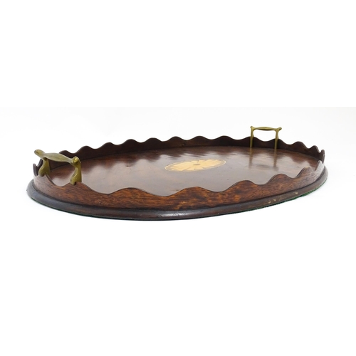 1262 - A Victorian mahogany tray of oval form with scalloped edge gallery, twin brass handles and inlaid sh... 