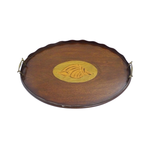 1262 - A Victorian mahogany tray of oval form with scalloped edge gallery, twin brass handles and inlaid sh... 