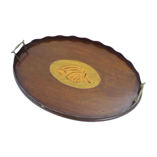 1262 - A Victorian mahogany tray of oval form with scalloped edge gallery, twin brass handles and inlaid sh... 