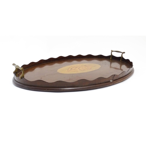 1262 - A Victorian mahogany tray of oval form with scalloped edge gallery, twin brass handles and inlaid sh... 