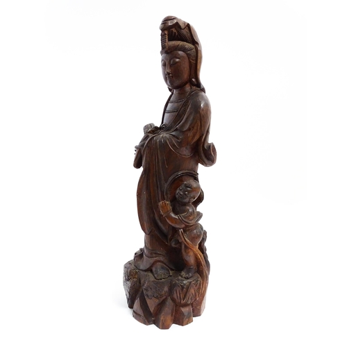 1282 - A Chinese carved hardwood model of Guanyin with a child. Approx. 20