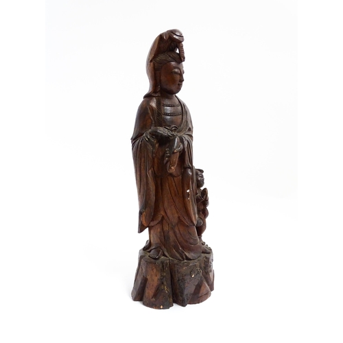 1282 - A Chinese carved hardwood model of Guanyin with a child. Approx. 20