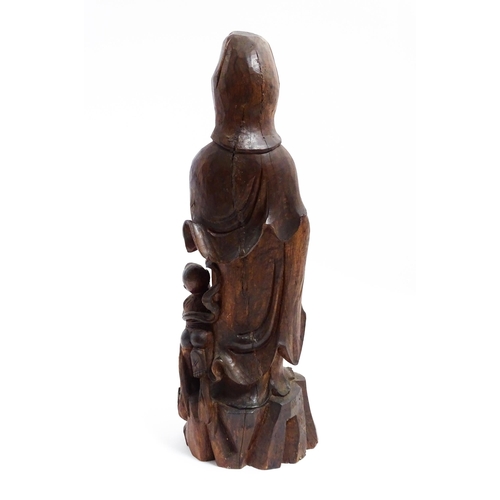 1282 - A Chinese carved hardwood model of Guanyin with a child. Approx. 20