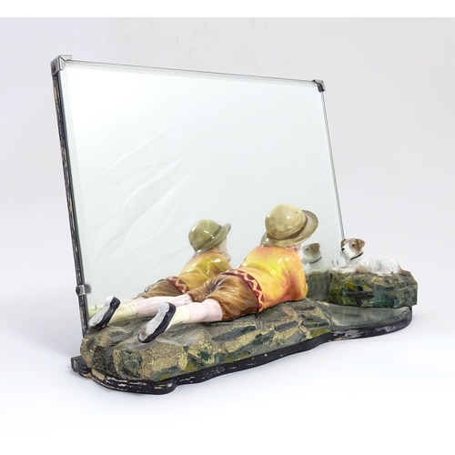 1294 - A 20thC Continental easel back mirror with a ceramic model of a young boy looking at a fox terrier d... 