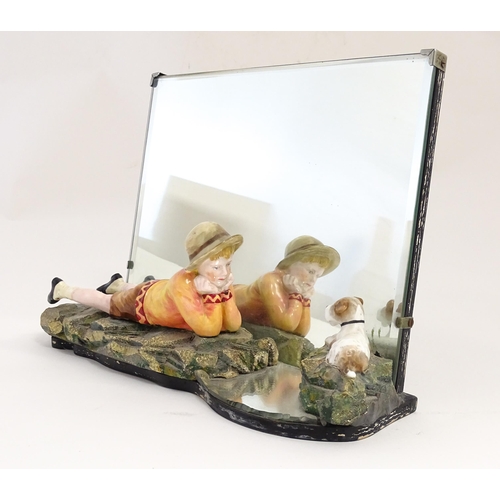 1294 - A 20thC Continental easel back mirror with a ceramic model of a young boy looking at a fox terrier d... 