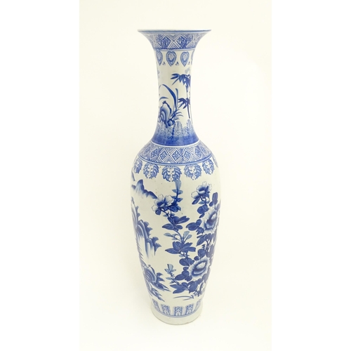 45 - A tall Chinese blue and white vase with a flared rim decorated with a landscape scene with flowers a... 