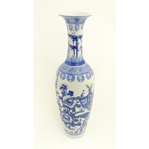 45 - A tall Chinese blue and white vase with a flared rim decorated with a landscape scene with flowers a... 