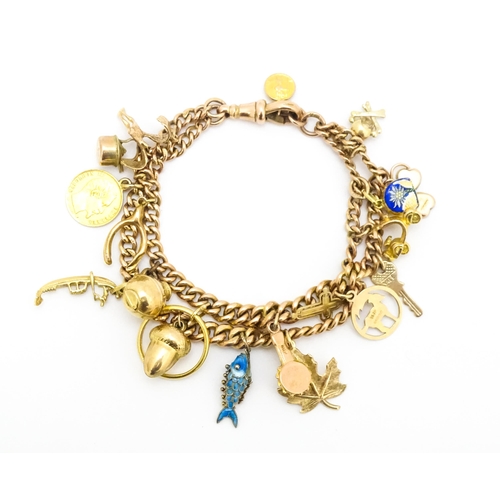 764 - A 9ct gold twin chain charm bracelet set with various 9ct gold and yellow metal charms to include a ... 