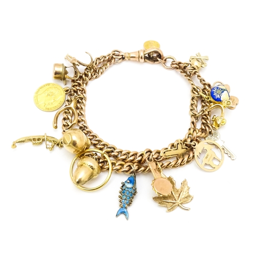 764 - A 9ct gold twin chain charm bracelet set with various 9ct gold and yellow metal charms to include a ... 