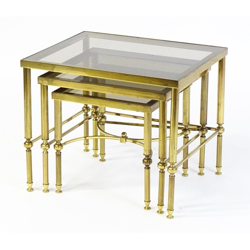 1637 - A nest of three tables with smoked glass tops and raised on reeded tapering legs. 22