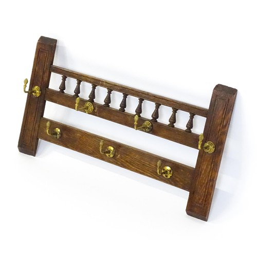 1511 - An early 20thC oak coat rack / hat rack with a finial turned back panel and seven brass hooks. 27