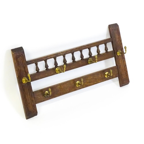 1511 - An early 20thC oak coat rack / hat rack with a finial turned back panel and seven brass hooks. 27