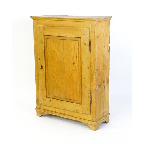 1531 - A 19thC pine cupboard with a moulded top above a single panelled door and raised on four bracket fee... 