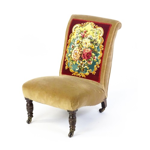 1536 - A late 19thC / early 20thC nursing chair with a needlework backrest, sprung seat and raised on taper... 