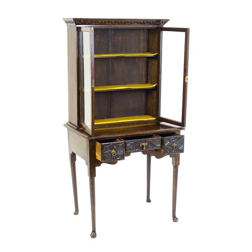 1538 - An early 20thC oak lowboy bookcase, with a moulded and carved cornice above two glazed doors. The lo... 