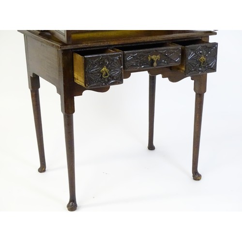 1538 - An early 20thC oak lowboy bookcase, with a moulded and carved cornice above two glazed doors. The lo... 