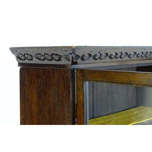 1538 - An early 20thC oak lowboy bookcase, with a moulded and carved cornice above two glazed doors. The lo... 