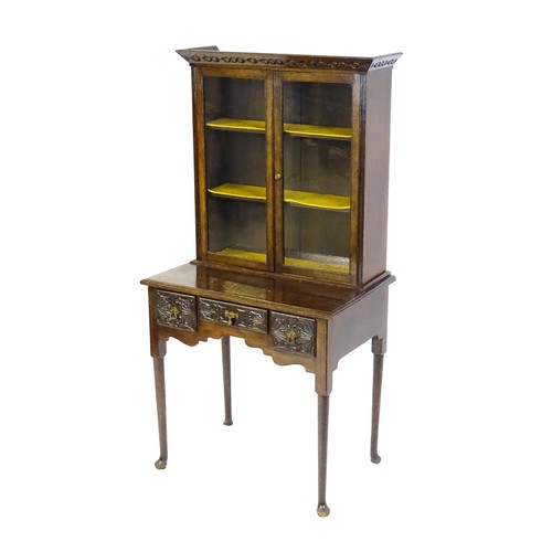 1538 - An early 20thC oak lowboy bookcase, with a moulded and carved cornice above two glazed doors. The lo... 