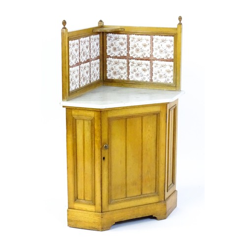 1557 - A late 19thC oak corner washstand, with a twelve tile splashback above a marble top and panelled cup... 