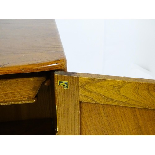 1629 - Vintage / Retro: An Ercol elm sideboard (model 366), the figured elm top above three panelled cupboa... 