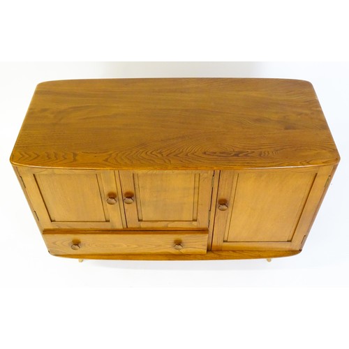 1629 - Vintage / Retro: An Ercol elm sideboard (model 366), the figured elm top above three panelled cupboa... 