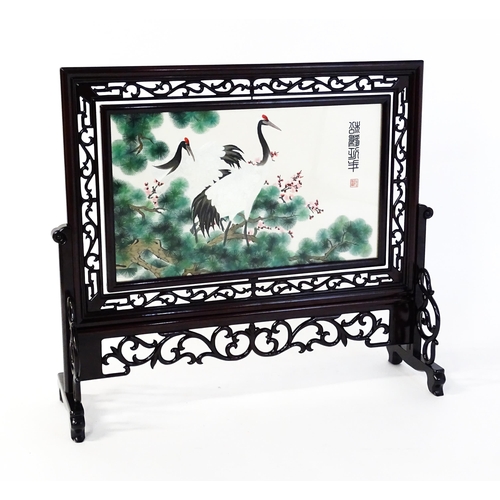 1280 - A Chinese embroidered table screen with carved hardwood frame and stand, the double sided embroidery... 