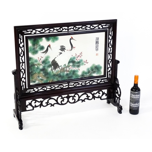 1280 - A Chinese embroidered table screen with carved hardwood frame and stand, the double sided embroidery... 