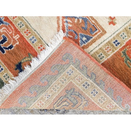 1341 - Carpet / Rug : A cream ground rug with dark salmon / terracotta borders, decorated with geometric an... 