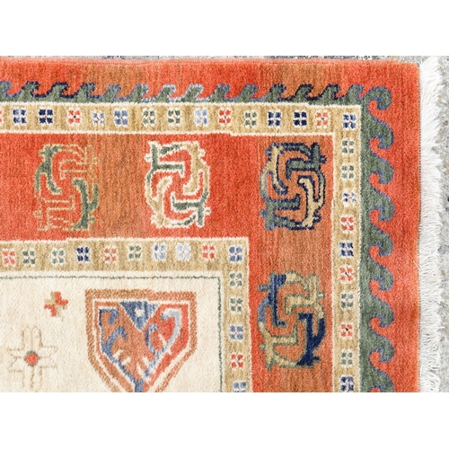 1341 - Carpet / Rug : A cream ground rug with dark salmon / terracotta borders, decorated with geometric an... 